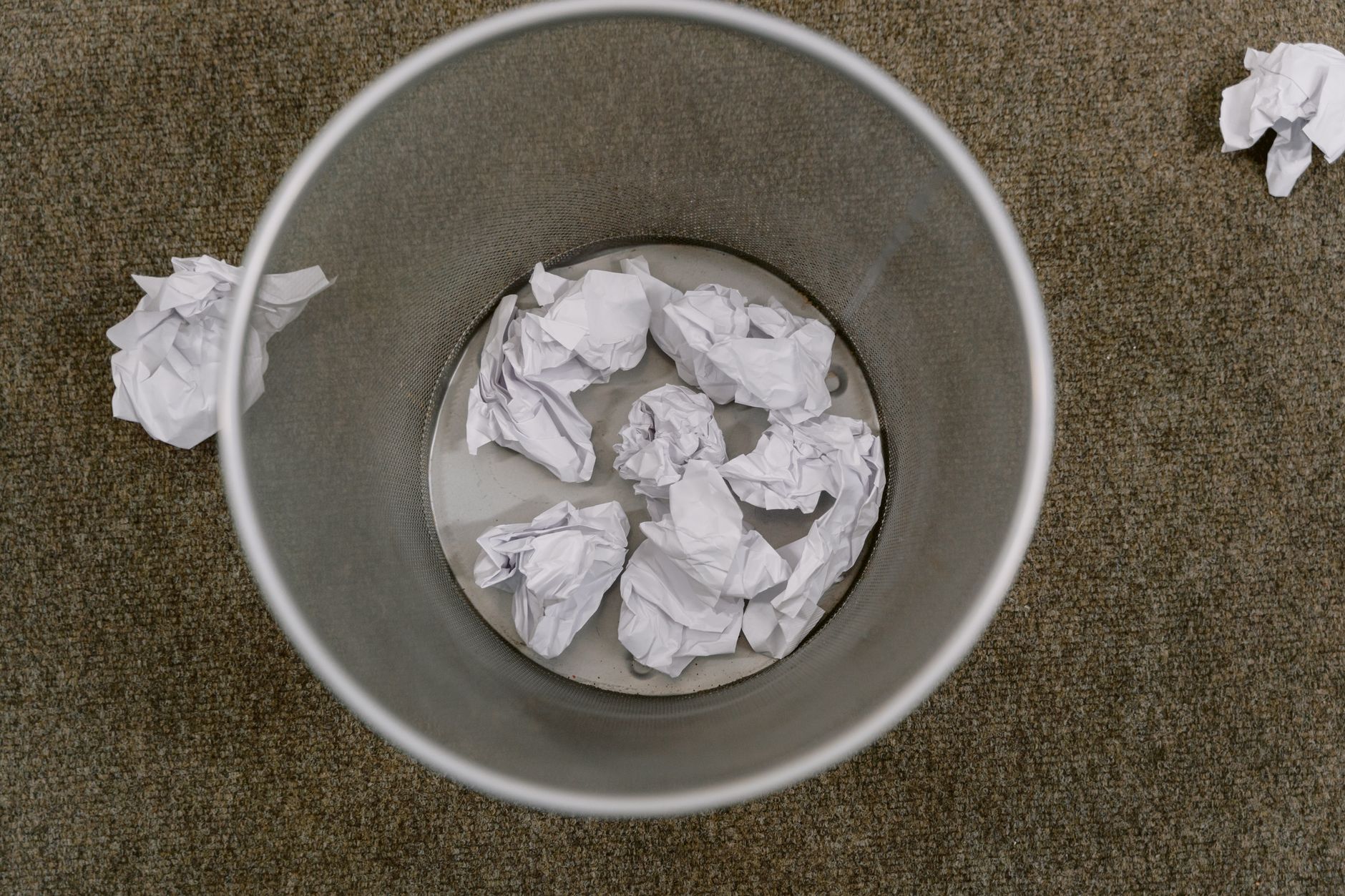a crumpled ball of foil sitting on a dark kitchen counter next to a trash can