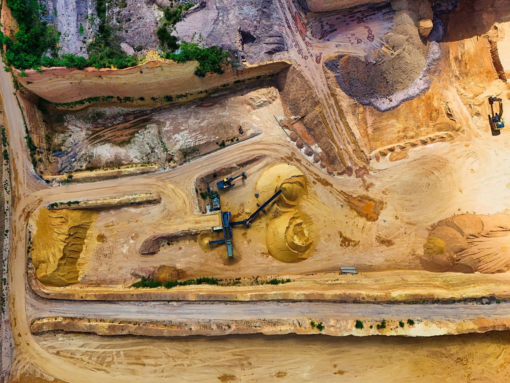 heavy excavators digging a deep trench in orange sand