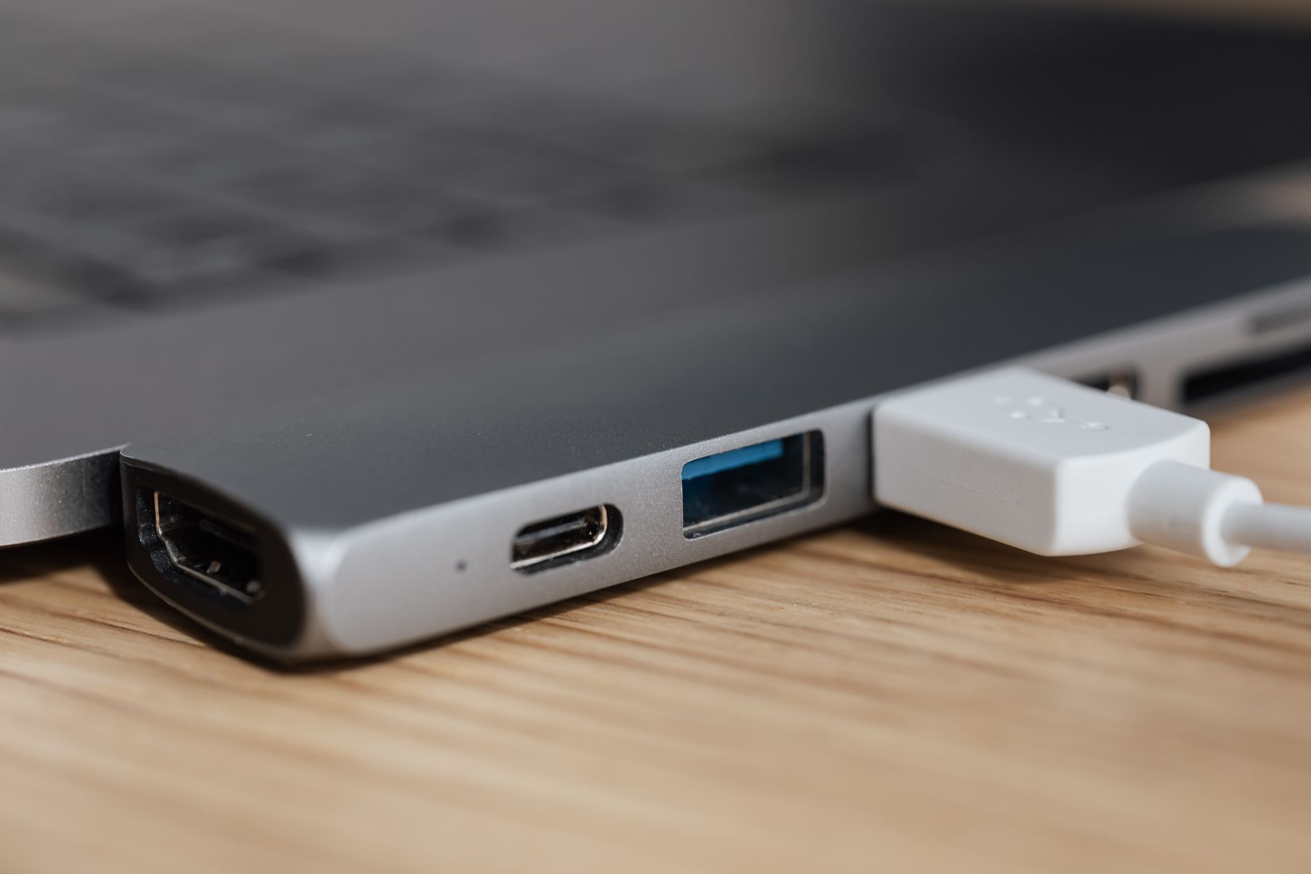 a handheld electronic device plugged into a laptop on a cluttered wooden desk