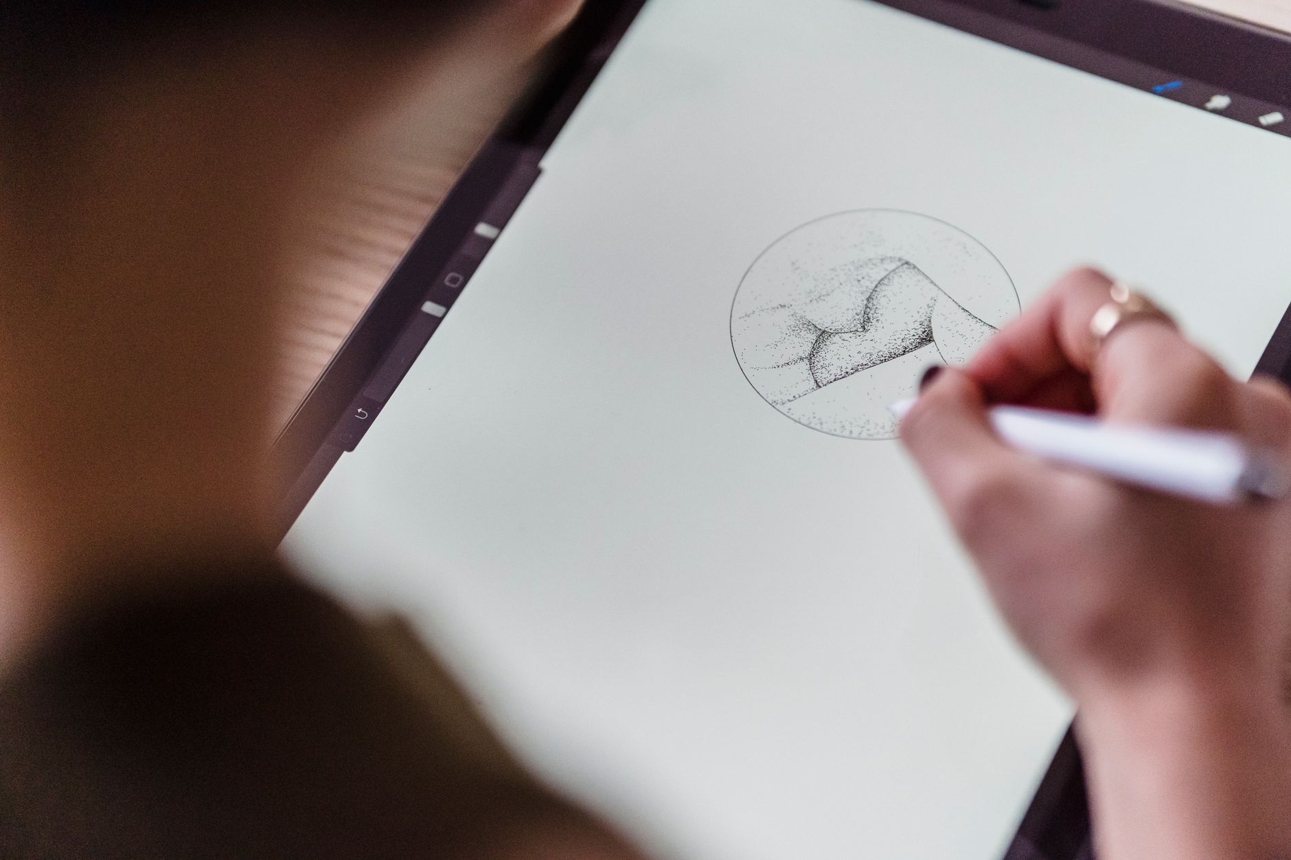 a hand holding a stylus over a stained parchment screen