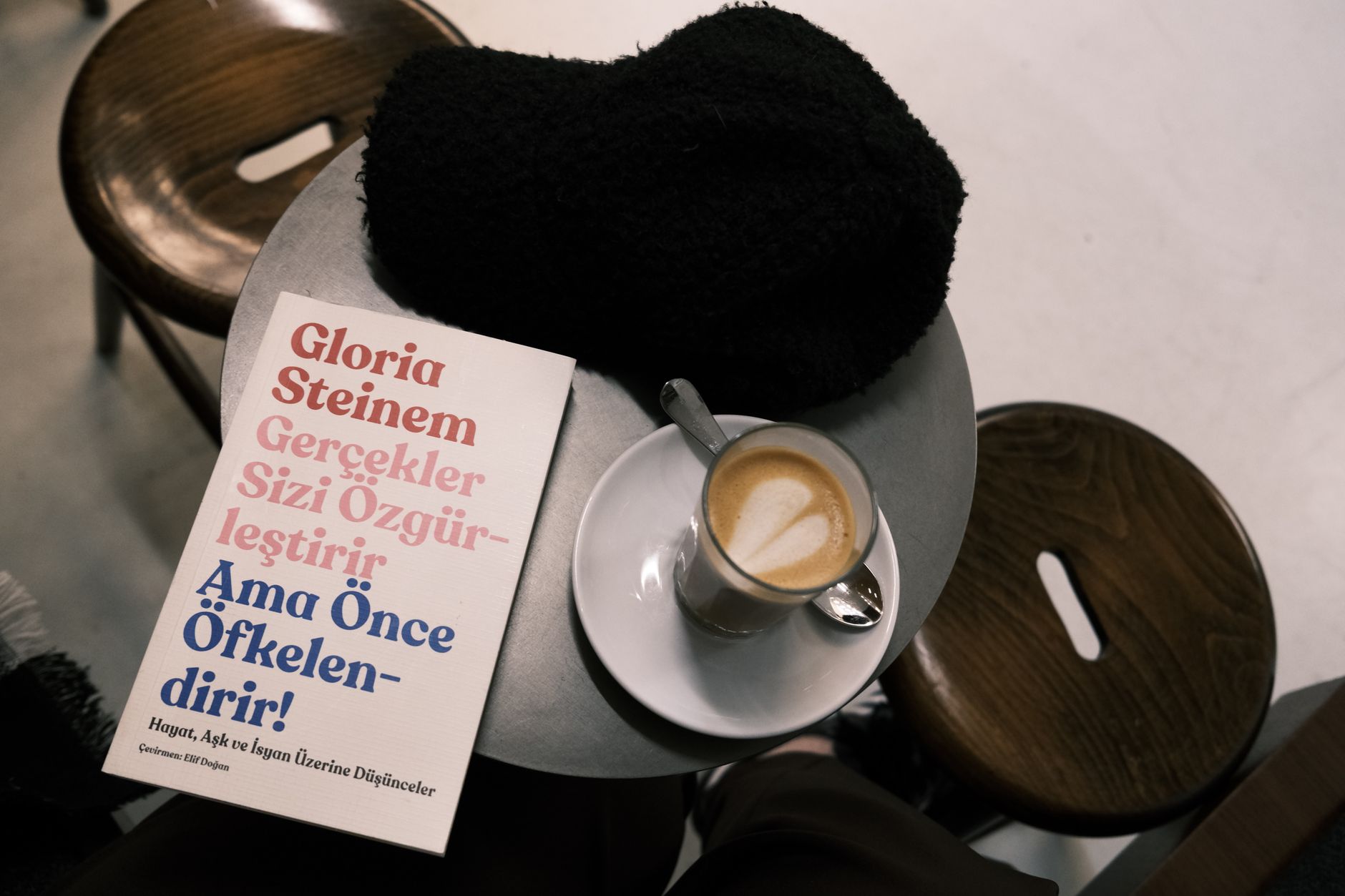 a pristine hardcover book resting on a marble bistro table next to an espresso