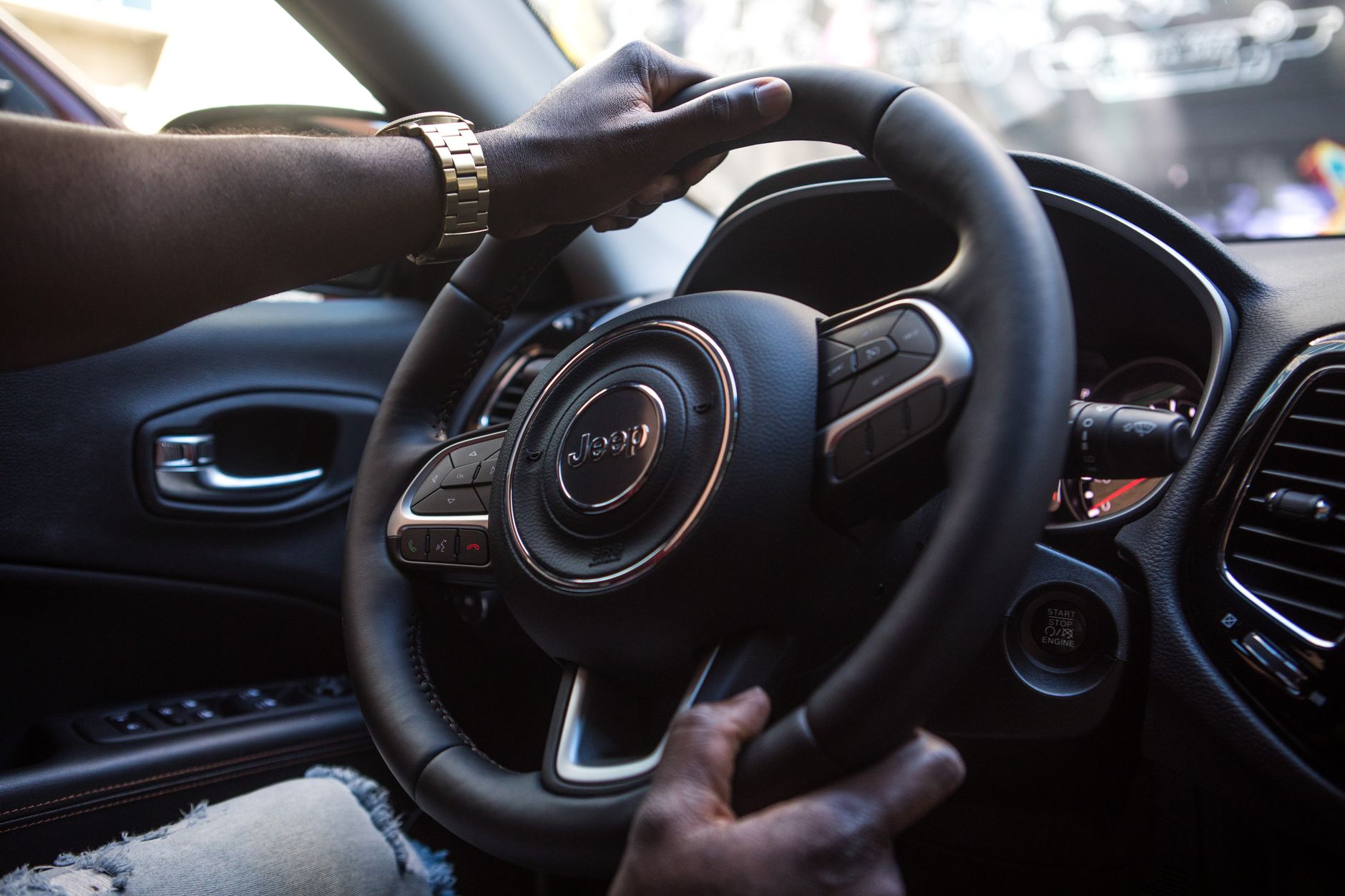 a man grimacing wildly at a car dashboard while holding the steering wheel